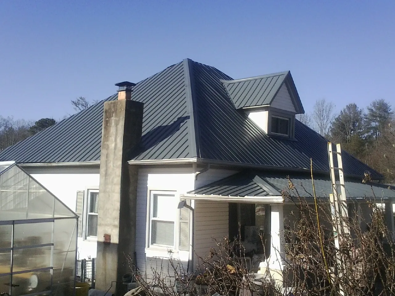 Dark blue standing seam metal roof on a white farmhouse with dormer — Slate & Tile Roof Repair by Roofing Brothers in Beaverton