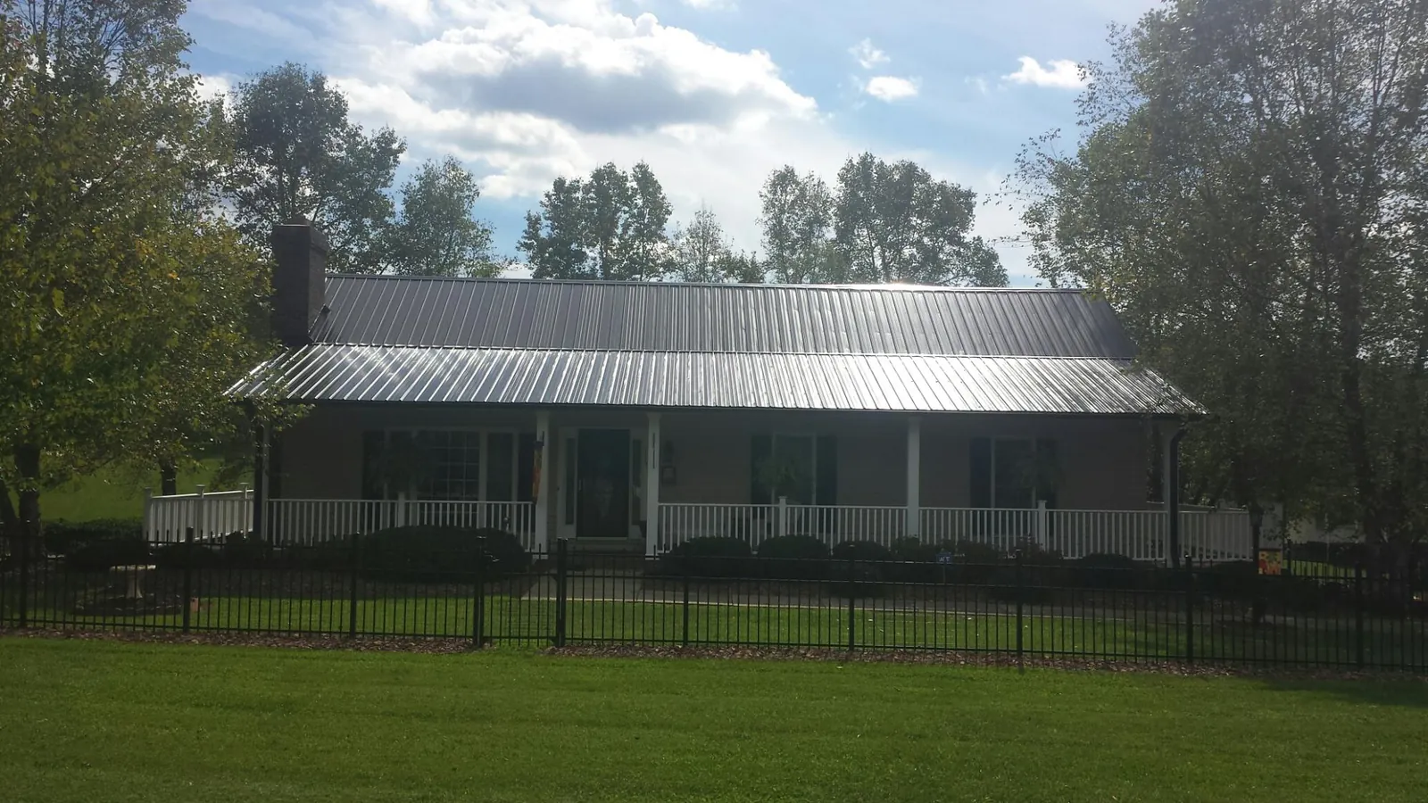 Gray metal roof on a brick ranch with a full width front porch — Gutter Guard Installation work by our crew in Beaverton
