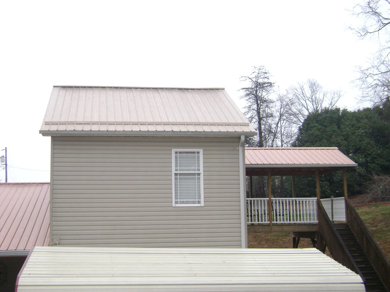 Tan metal roofs on a two story addition and attached porch, from a Roof Replacement job in Beaverton