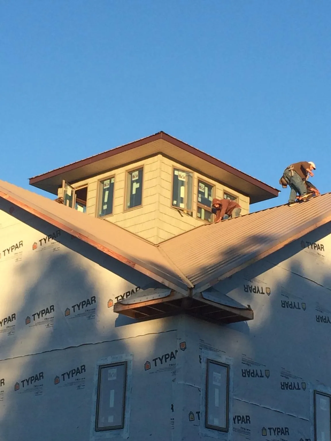 Roofers working around a rooftop cupola on a new metal roof at sunset — Roof Waterproofing in Beaverton by Roofing Brothers